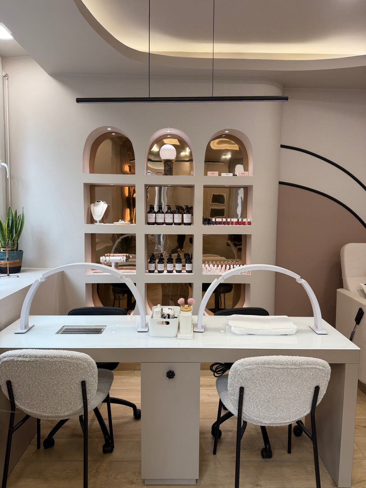Poste de manucure Emioli : table blanche, lampes en arc et étagère en arches garnie de vernis et de soins