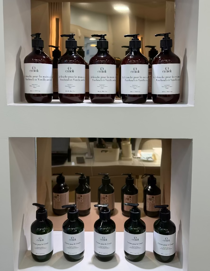 Gels douche et crèmes pour le corps Emioli rangés sur deux étagères blanches