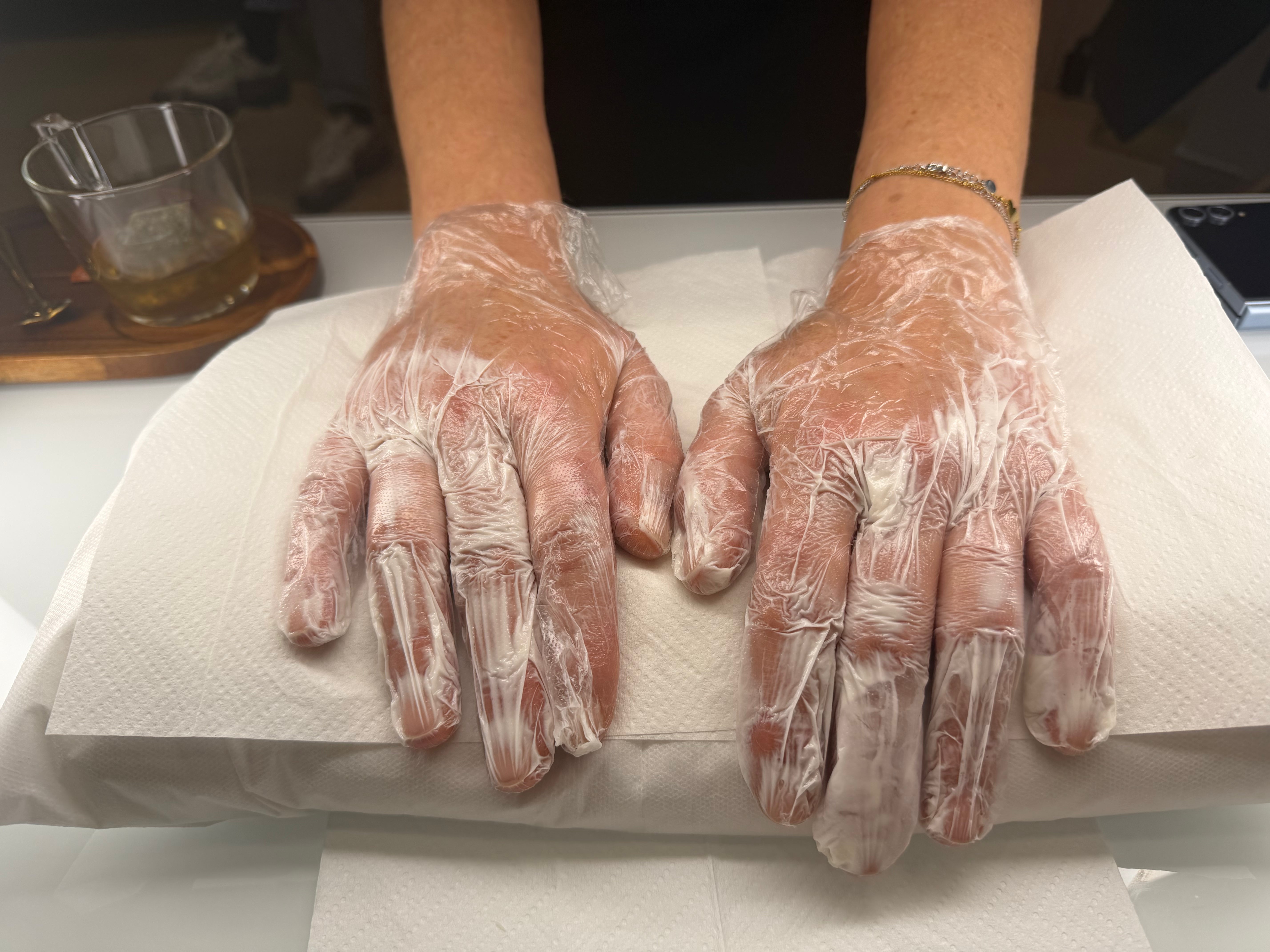Mains enduites de crème et recouvertes de gants pendant un soin des mains